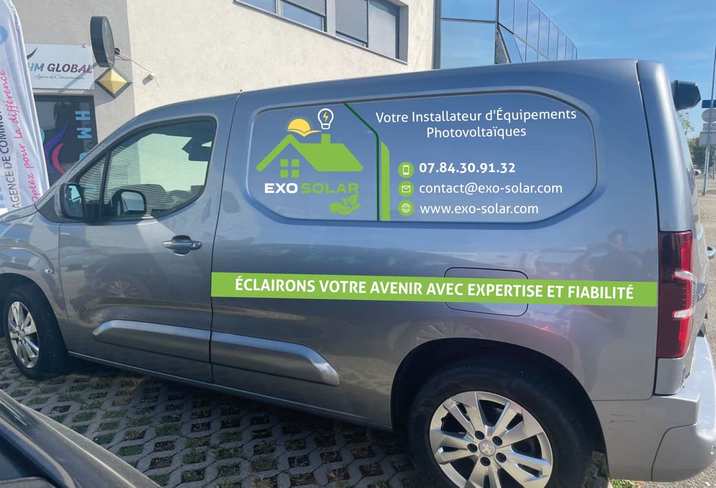 Berlingo gris lettré Exo Solar, photographié devant l'agence HM Global